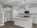 Bright kitchen featuring white cabinets, stainless steel appliances, and quartz countertops at 104 Fairwinds Dr, Lillington, NC 27546