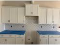 Kitchen cabinets with decorative backsplash and white cabinets at 104 Fairwinds Dr, Lillington, NC 27546
