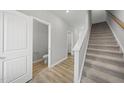 Bright hallway featuring a staircase, wood-look flooring, a half bathroom, and white trim throughout at 104 Ripple Way # 318, Clayton, NC 27520