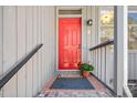 Close-up of a vibrant red front door with a brick stoop and pot of flowers at 2 Edgestone Pl, Chapel Hill, NC 27517