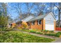 Charming brick home featuring mature trees and a well-maintained lawn with attached garage at 2203 Canterbury Dr, Burlington, NC 27215