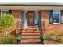 Inviting front porch with decorative wreath, cozy seating, and well manicured landscaping at 2203 Canterbury Dr, Burlington, NC 27215
