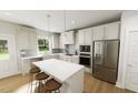 Bright, modern kitchen features white cabinetry, stainless steel appliances and an island with bar seating at 296 Beacon Dr, Pittsboro, NC 27312