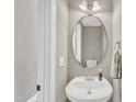 Cozy powder room with a pedestal sink, oval mirror, and neutral wall color at 3001 Imperial Oaks Dr, Raleigh, NC 27614