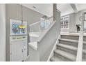 Bright stairway featuring gray walls, white railings, carpeted stairs, and a front door view at 3001 Imperial Oaks Dr, Raleigh, NC 27614