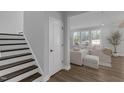 Bright living room featuring hardwood floors, large windows, and stairs leading to the upper floor at 3360 Brevet St, New Hill, NC 27562
