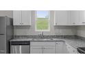 Bright, efficient kitchen with stainless dishwasher and sink, granite counters, and white cabinets at 65 Crow Field St, Roxboro, NC 27574