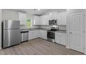 Bright kitchen features white cabinets, stainless steel appliances, granite counters and wood-look floors at 65 Crow Field St, Roxboro, NC 27574