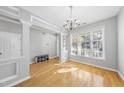 Bright dining room featuring beautiful hardwood floors, crown molding, a modern chandelier, and lots of natural light at 7707 Oak Marsh Dr, Raleigh, NC 27616