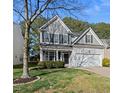 Charming two-story home boasts gray siding, black shutters, lush landscaping, and an attached two-car garage at 7707 Oak Marsh Dr, Raleigh, NC 27616