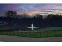 Scenic pond view with a fountain, surrounded by mature trees and manicured landscaping at 8005 Woodcross Way, Wake Forest, NC 27587