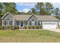 Close up of a charming home with stone accents, gray siding, an oval front door, and a manicured lawn at 808 Cross Link Dr, Angier, NC 27501