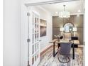 Home office with neutral walls, chandelier, modern desk, and decorative rug through a double door at 1010 Red Roses Ave, Durham, NC 27703