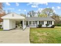 Daytime view of a charming single-story home featuring a connected carport, manicured lawn, and a welcoming front porch at 118 Tysor Cir, Graham, NC 27253