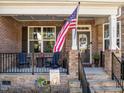 Cozy front porch with stone accents, seating, and a welcoming American flag at 1824 Longmont Dr, Wake Forest, NC 27587