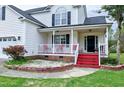 Lovely home featuring a cozy front porch with red steps and chairs, complemented by meticulous landscaping and shrubbery at 2709 White Rail Dr, Fuquay Varina, NC 27526