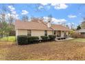Tan-sided home, showcasing neat shrubbery, a peaked roof, and a welcoming front porch under a partly cloudy sky at 3490 Old Buies Creek Rd, Angier, NC 27501