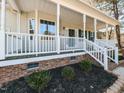 Inviting front porch with white railings, brick accents, and manicured landscaping at 382 Tomahawk Dr, Clayton, NC 27520