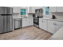 Well-lit kitchen featuring stainless steel appliances, white cabinets, and modern flooring at 4408 Poplar Dr, Raleigh, NC 27610