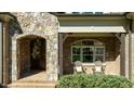 Inviting front porch featuring brick flooring, chairs, decorative door with stone surround and window at 1009 High Trail Ct, Wake Forest, NC 27587