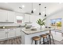 Bright kitchen with white cabinets, granite countertops, an island with bar seating, and modern pendant lighting at 1208 Wind Rose Dr, Fuquay Varina, NC 27526