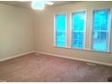 Bright bedroom featuring three large windows and neutral carpet at 1505 Harth Dr, Garner, NC 27529