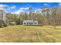 A picturesque one-story home sits on a grassy lot with mature trees in the background under a blue sky at 188 Hunter Ln, Zebulon, NC 27597