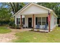 Inviting front exterior featuring a quaint porch with seating, American flag, and manicured landscaping at 501 E Granville St, Dunn, NC 28334