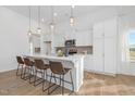 Modern kitchen features a large island with seating, pendant lighting, and white cabinets at 63 Mable Court # 6, Lillington, NC 27546