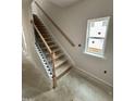 View of a home's staircase featuring wood railing, black balusters, and natural light from a window at 76 Commons Cir, Clayton, NC 27520