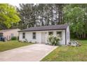 Inviting single-story home with white siding, black trim, landscaping and a concrete driveway at 1204 Pecan Pl, Durham, NC 27704