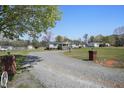 Gravel driveway leading to a single-story home, complemented by a large yard and a detached shed at 122 Blueberry Dr, Selma, NC 27576