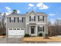 Two-story home with gray siding, black shutters, a gray roof and a white garage door at 1423 Bridgewater Dr, Durham, NC 27704