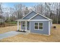 Charming single-story home with light gray siding, a front porch and green roof surrounded by dormant trees at 175 David Ln, Roxboro, NC 27573