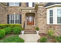 Elegant front entrance with wood door, detailed brickwork, and lush landscaping at 1808 Pattersons Mill Rd, Durham, NC 27703