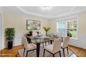 Bright dining room boasts elegant wainscoting, modern light fixture, and a glass table with seating for six at 198 Hillsdale Dr, Archer Lodge, NC 27527