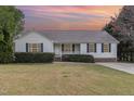 Classic house with a cozy front porch, blue shutters, and a well-kept lawn under a colorful sky at 201 Alice Dr, Garner, NC 27529