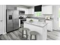 Well-lit kitchen featuring white cabinets, stainless steel appliances, and a functional center island with bar stools at 221 N Coral Bells Way, Four Oaks, NC 27524