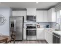 Modern kitchen featuring stainless steel appliances, white cabinets, light countertops, and hardwood flooring at 231 N Coral Bells Way, Four Oaks, NC 27524