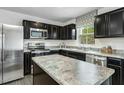 Modern kitchen featuring stainless steel appliances, dark cabinetry, and an island with a light countertop at 231 N Coral Bells Way, Four Oaks, NC 27524
