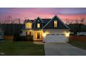Beautiful two-story home with warm exterior lights illuminating the yard and driveway at dusk at 36 Deep Woods Ln, Cameron, NC 28326