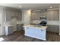 Open kitchen features gray cabinets, an island with a sink, white subway tile, and stainless steel appliances at 4012 Shadbush St, Raleigh, NC 27616