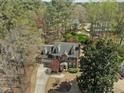 Aerial view of a brick two-story home with green roof surrounded by mature trees and lush lawn at 5125 Salinas Ct, Holly Springs, NC 27540