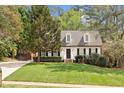 Charming home with white siding, black shutters, dormer windows, brick stairs, and a lush front lawn at 7616 Valley Run Dr, Raleigh, NC 27615