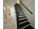 Staircase with dark wood steps and railing with view of the kitchen and hallway at 779 Old Station Pointe, Angier, NC 27501