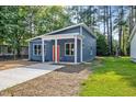 Modern-style home featuring a blue exterior, a covered front porch, an orange door, and surrounded by lush trees at 812 East St, Smithfield, NC 27577