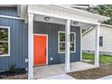 Close-up of a home's covered front porch with white columns, a vibrant orange door, and dark blue siding at 812 East St, Smithfield, NC 27577