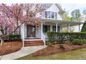 Inviting home entrance featuring a covered front porch, brick steps and blossoming tree at 101 Goldenthal Ct, Cary, NC 27519