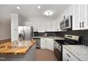 Well-lit kitchen features granite countertops, stainless steel appliances, and a wood-topped island at 1023 Kelton Cottage Way, Morrisville, NC 27560