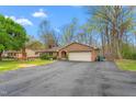 Brick home featuring an attached garage and a spacious driveway, all surrounded by lush greenery at 1525 Rogers Rd, Graham, NC 27253